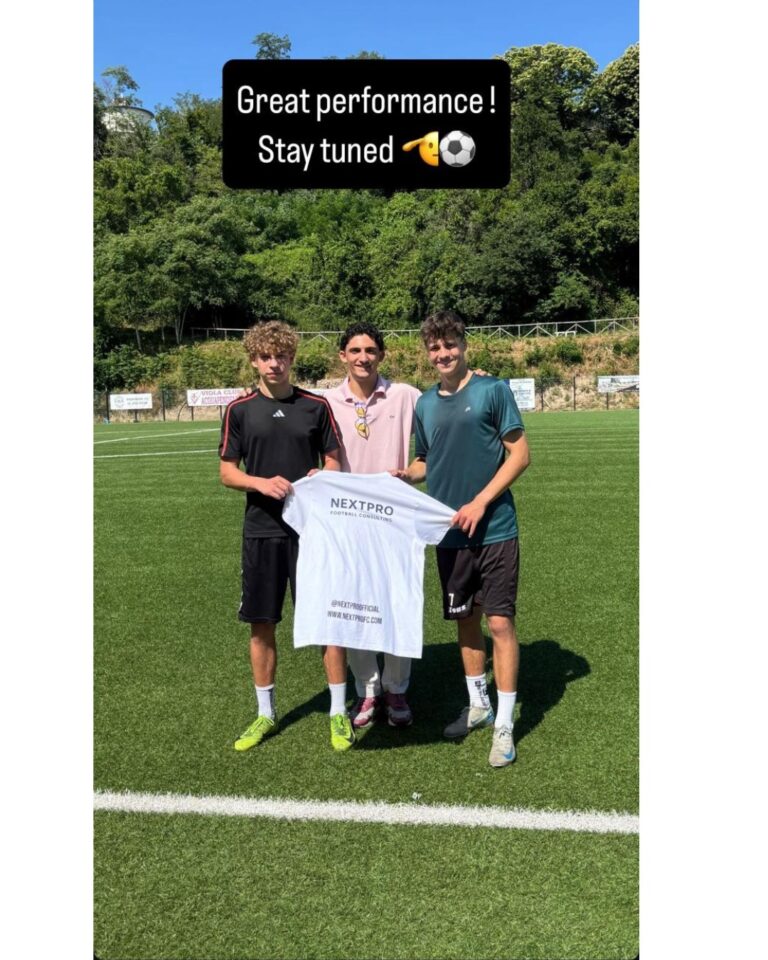 Three people on the pitch pose for a photo wearing a T-shirt